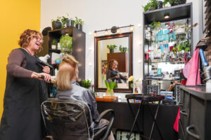 Stylist blow drying woman's hair in salon