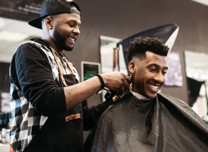 Barber cutting man's hair in a salon.